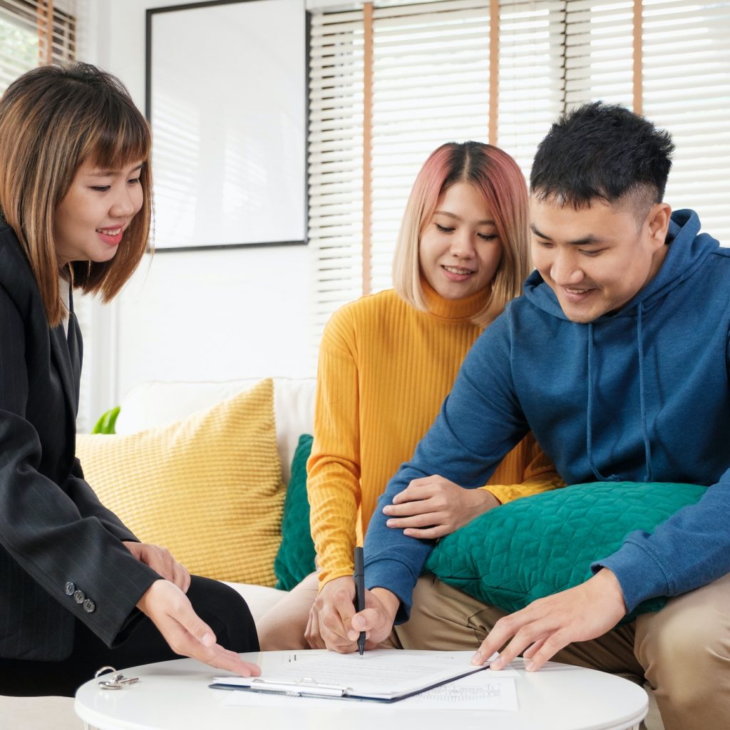Asian couple sign home contract and handshake with realtor at living room