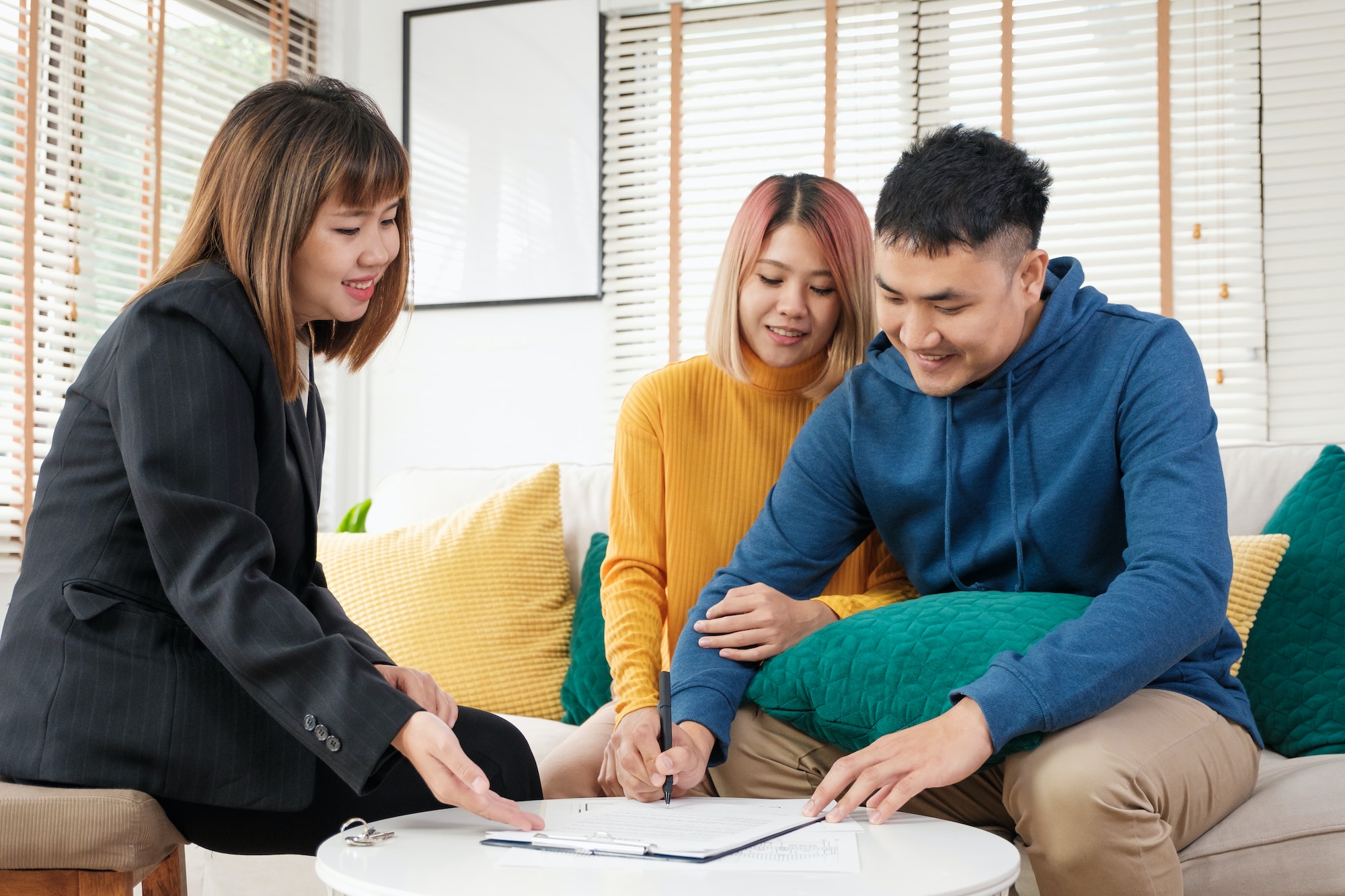 Asian couple sign home contract and handshake with realtor at living room